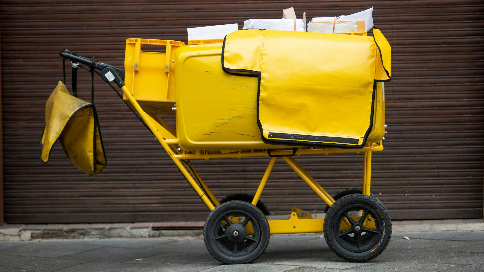 Ein Briefträgerwagen der Deutschen Post für die Hausbelieferung steht auf einer Straße.
