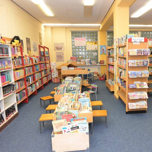 Zu sehen sind Bücherregale sowie Lesetische für Kinder und Erwachsene.