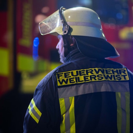 Ein Feuerwehrmann der Weilerswister Feuerwehr sichert in der Dunkelheit eine Unfallstelle ab.