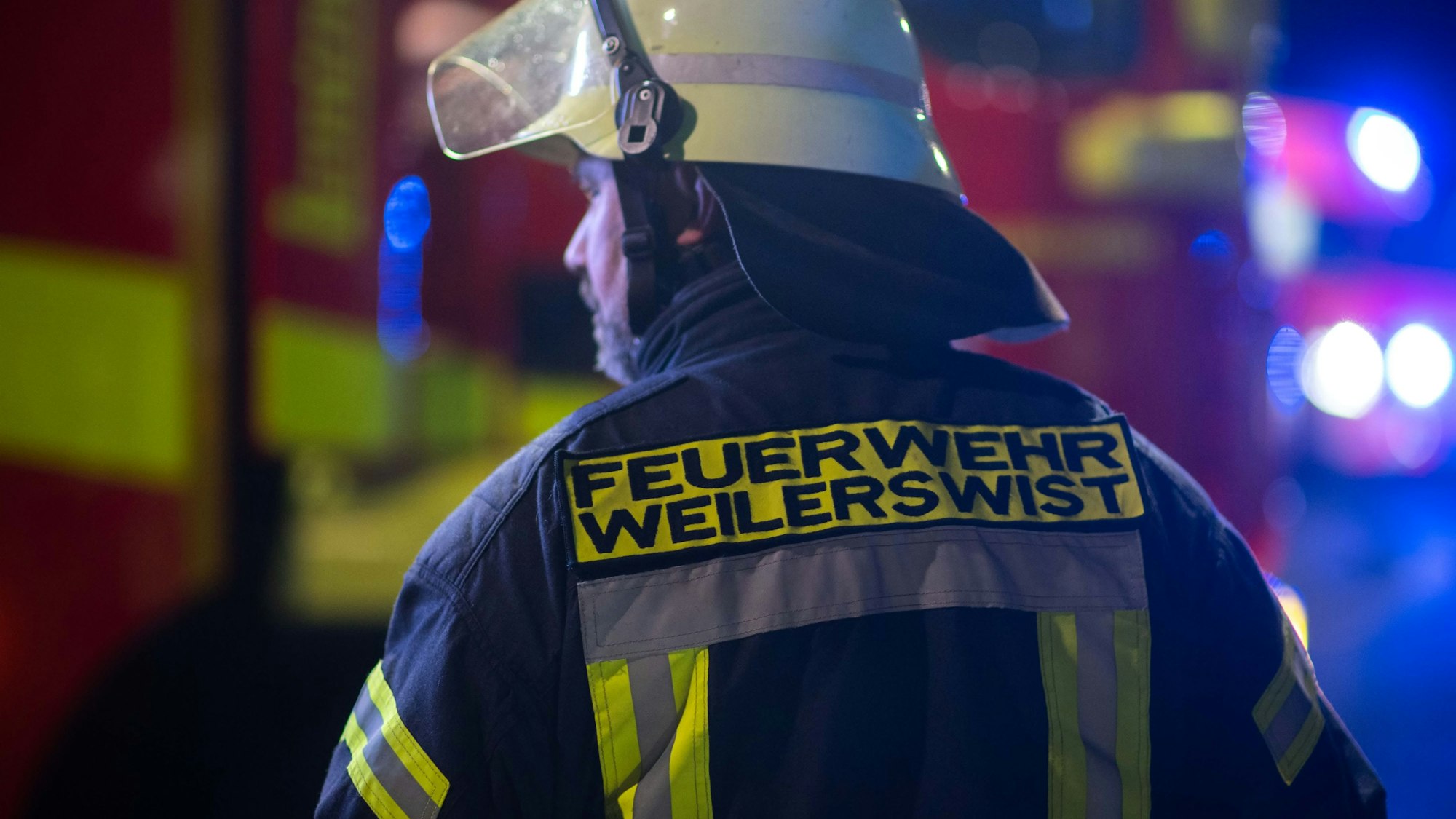 Ein Feuerwehrmann der Weilerswister Feuerwehr sichert in der Dunkelheit eine Unfallstelle ab.