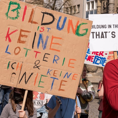 Ein Kind hält auf einer Demo ein selbst bemaltes Schild hoch.