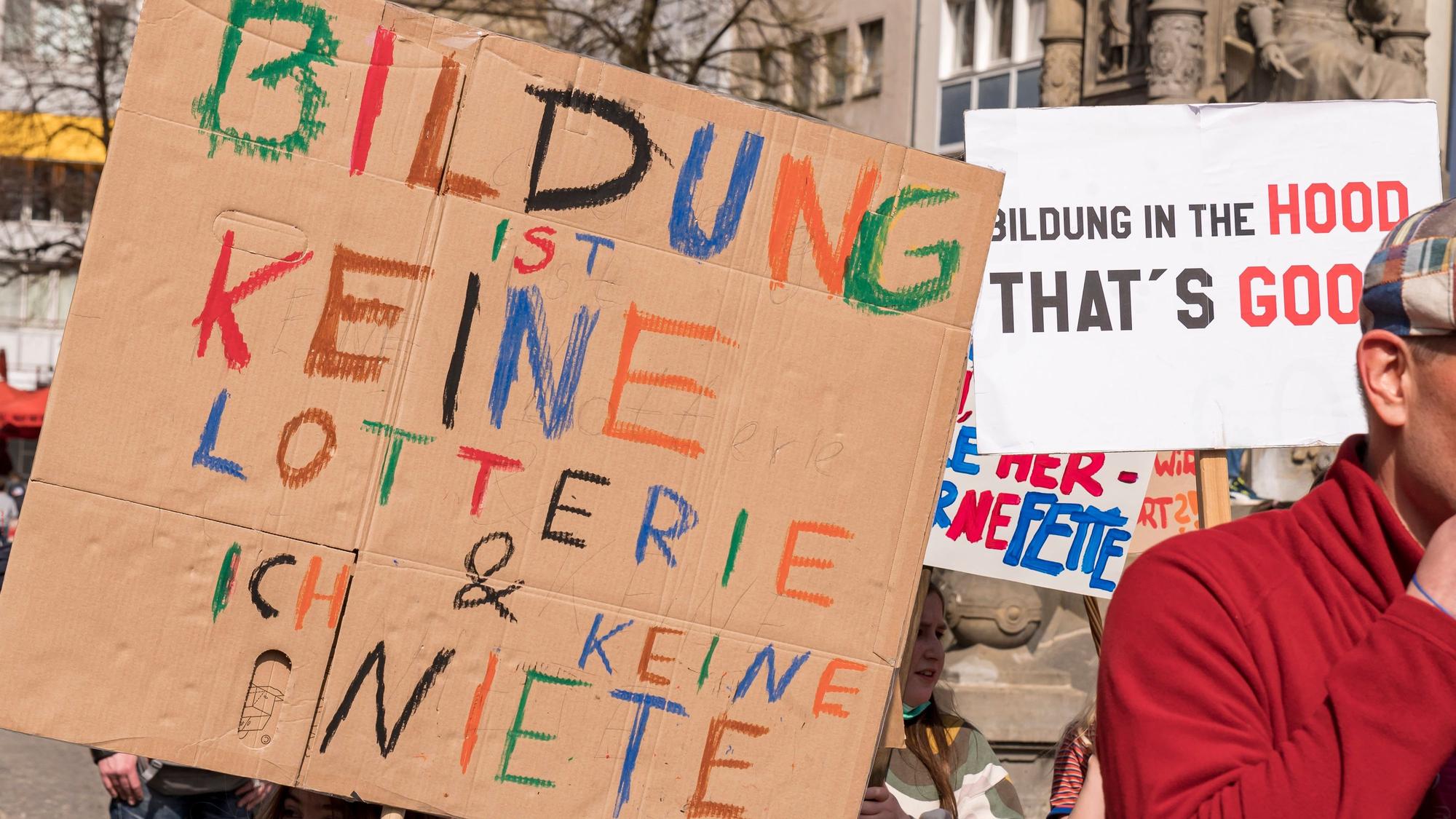 Ein Kind hält auf einer Demo ein selbst bemaltes Schild hoch.