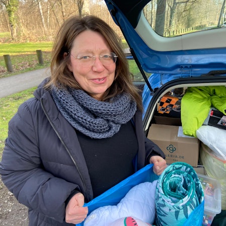 Sabine Frömel steht vor dem Kofferaum eines voll bepackten Autos