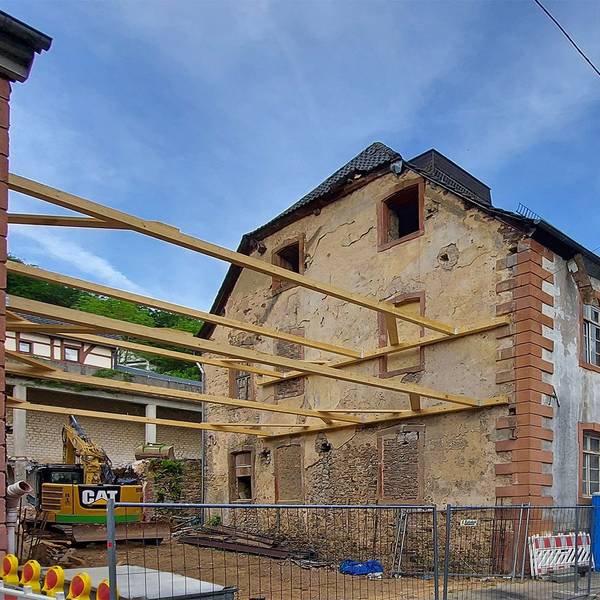 Vor einem alten Haus, das umgebaut wird, stehen Container.