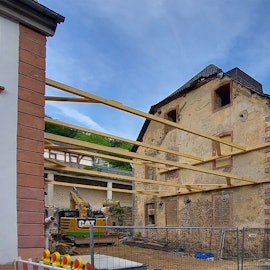 Vor einem alten Haus, das umgebaut wird, stehen Container.