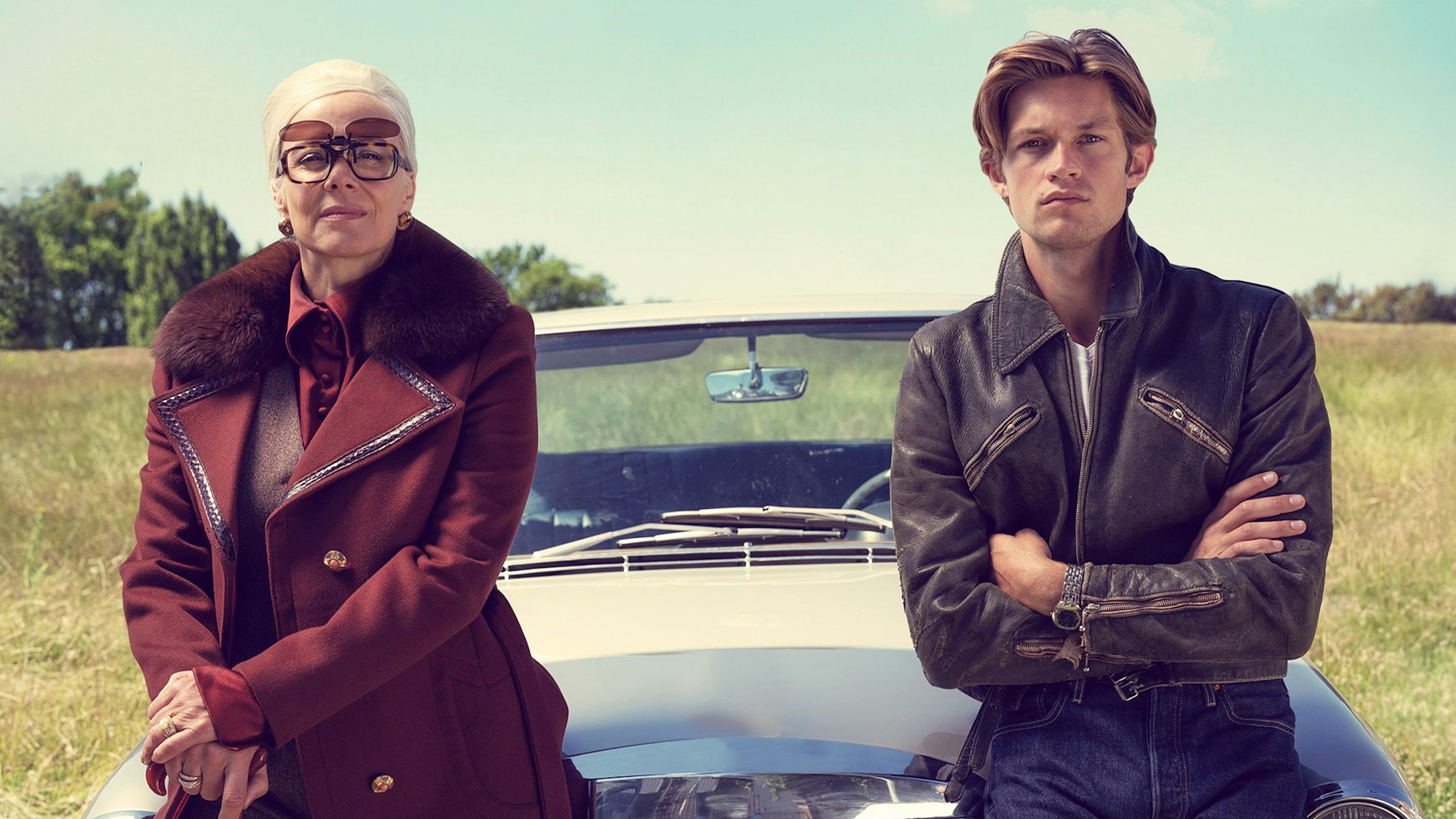 Katja Riemann und Damian Hardung sitzen auf einem Auto, das auf einem Feldweg steht.