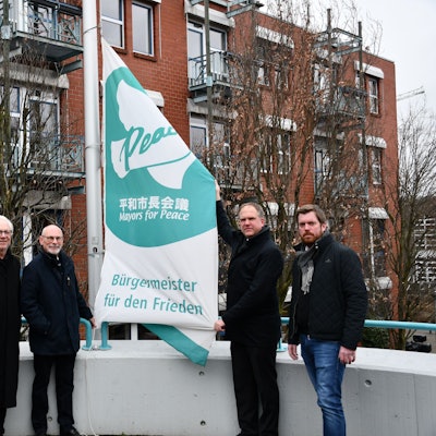 Das Foto zeigt, wie unter anderem Hürths Bürgermeister Dirk Breuer die „Mayors for Peace“-Flagge hisst.