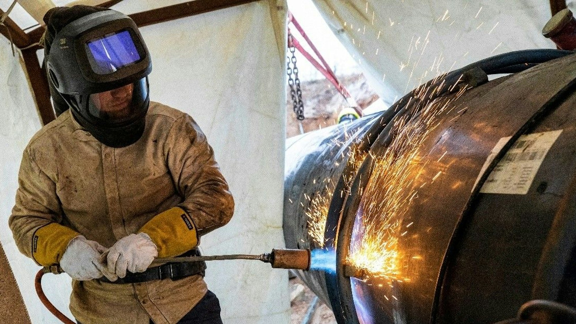 Ein Mann schließt mit einem Schweißgerät eine Naht an der umstrittenen Ferngasleitung rund um Leverkusen.