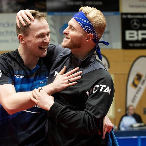 Zwei Tischtennisspieler liegen sich lachend in den Armen.