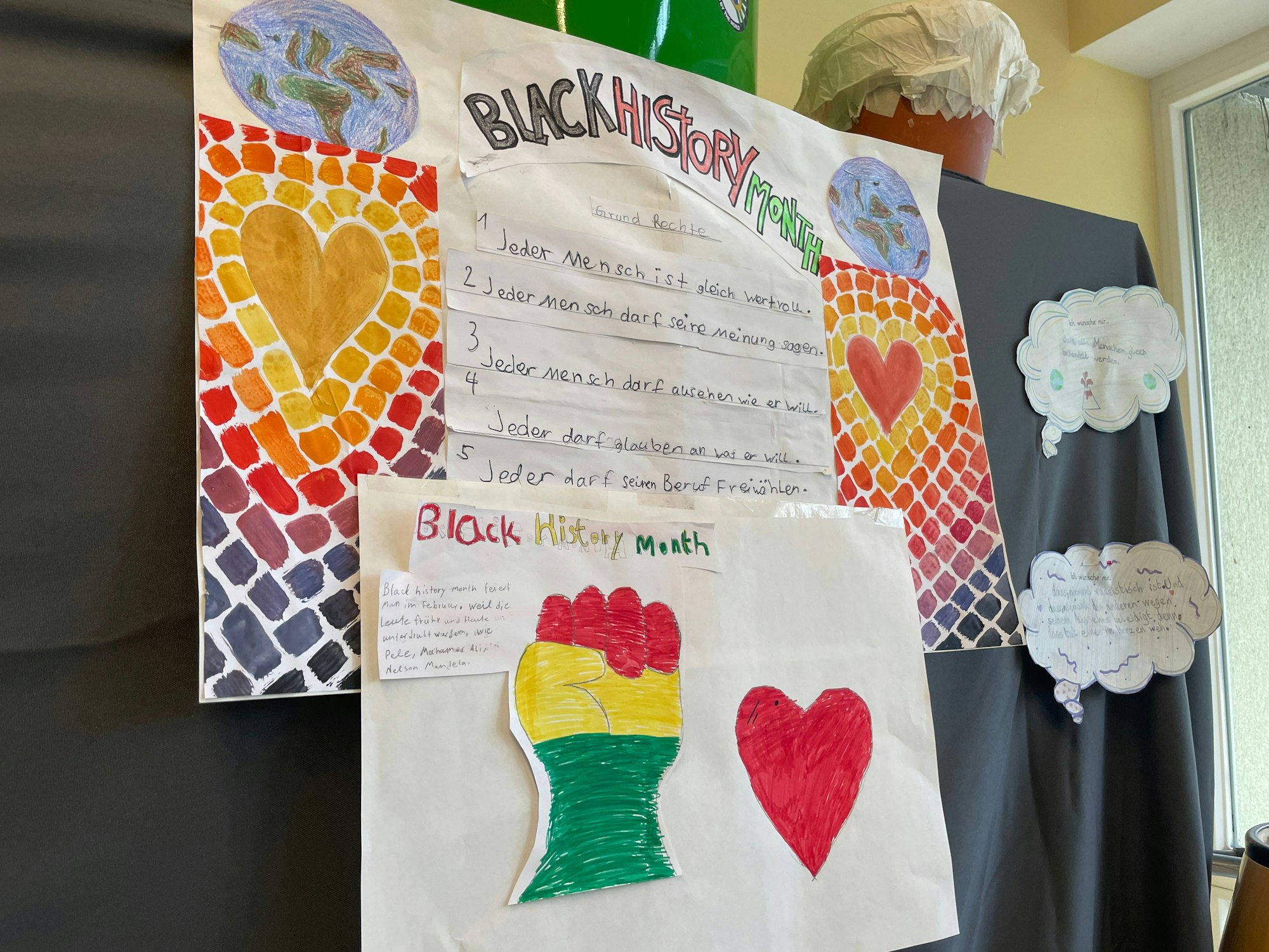 Auf einem bunten Poster steht das Grundgesetz in Handschrift geschrieben. Darüber und darunter steht „Black History Month“ geschrieben.