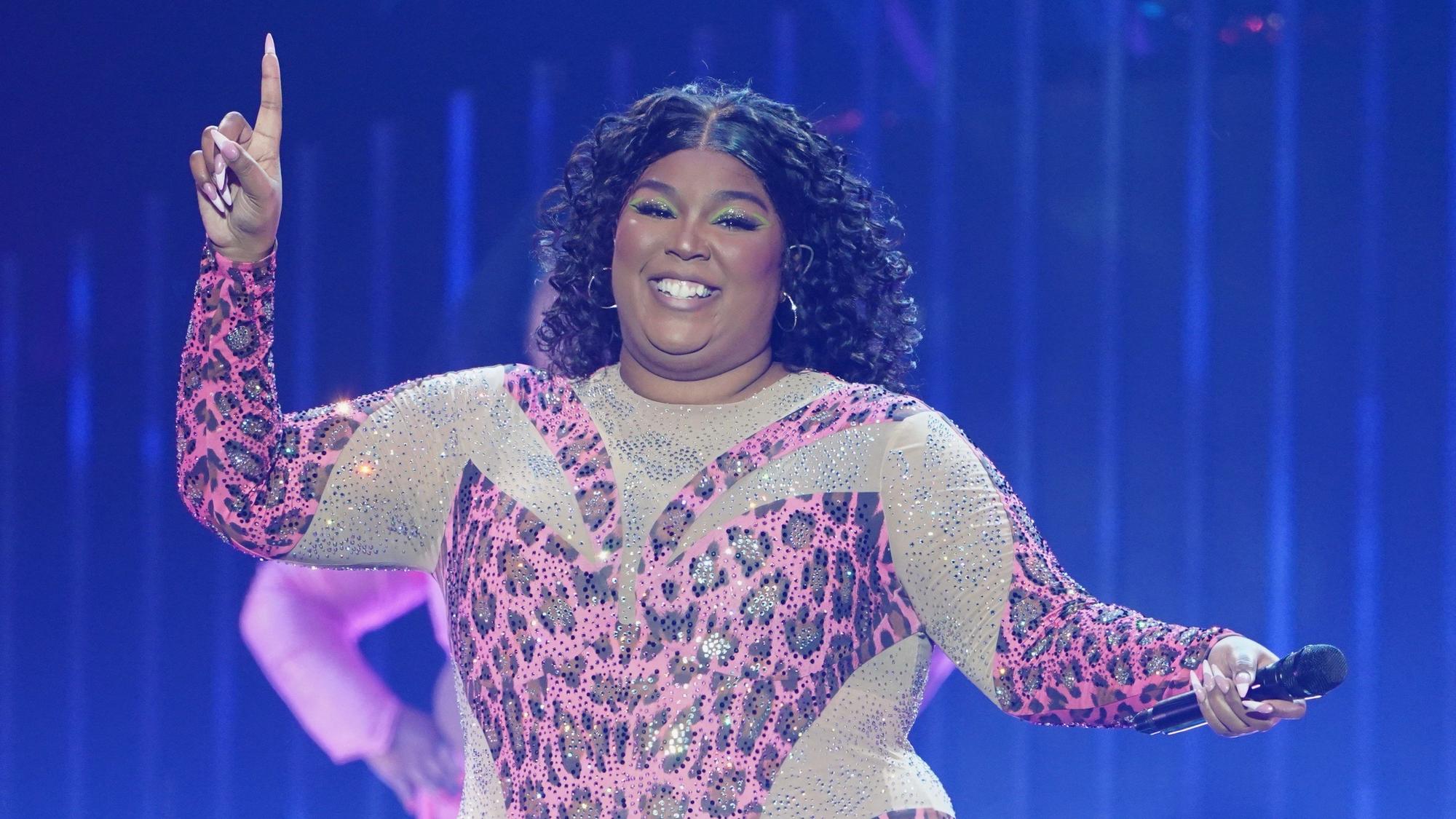 Die US-amerikanische Sängerin Lizzo steht in einem funkelden Anzug im Leoparden-Look auf der Bühne.