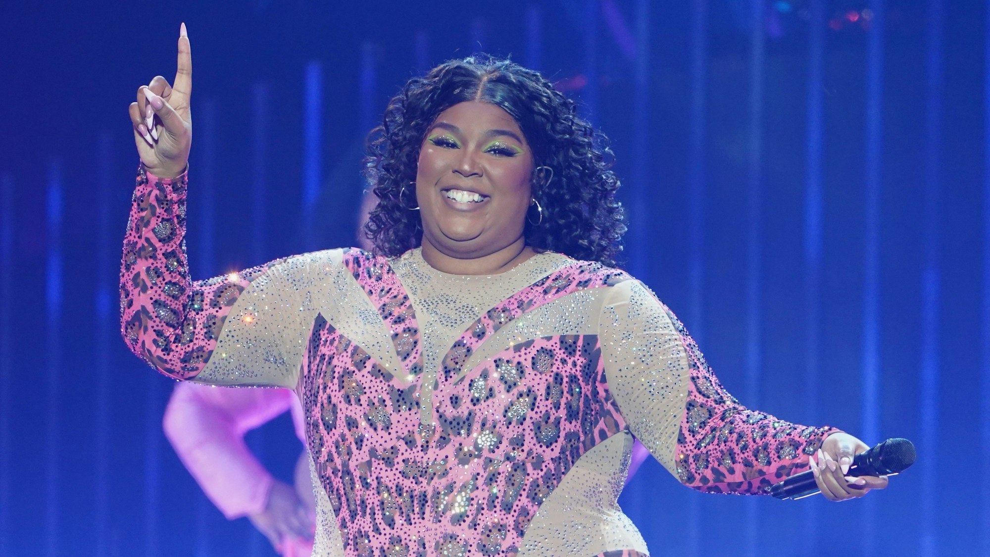 Die US-amerikanische Sängerin Lizzo steht in einem funkelden Anzug im Leoparden-Look auf der Bühne.