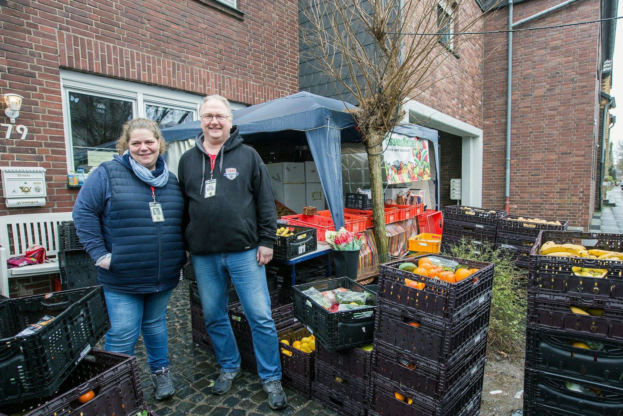 Mareike Berchem und Andreas Prinz stehen zwischen Kister voller Obst und Gemüse.