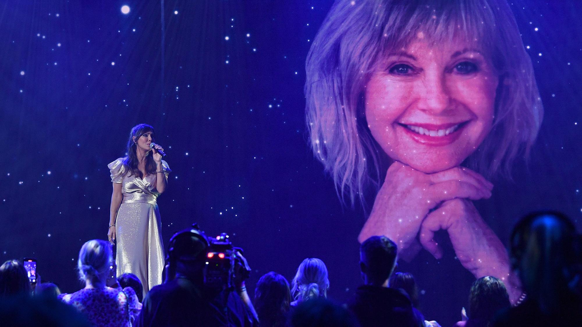 Natalie Imbruglia singt, im Hintergrund ein Bild von Olivia Newton-John