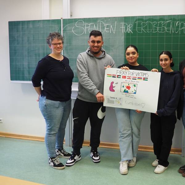 Die Schüler und Lehrer der Leverkusener Gesamtschule halten ein Plakat ihres Kuchenverkaufs vor.