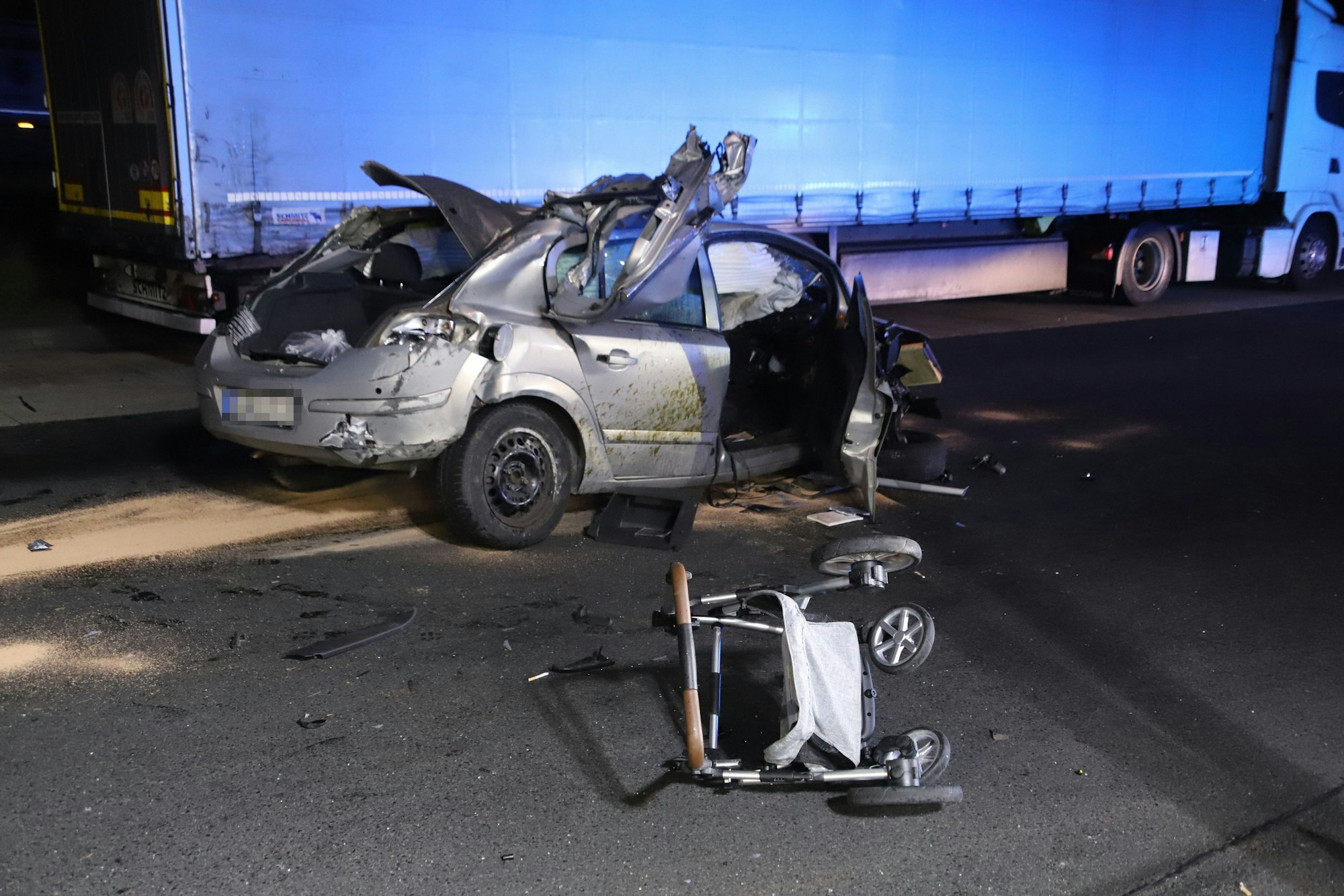 Ein extrem verbeultes Auto steht an der Raststätte Siegburg-Ost, davor liegt ein Kinderwagen.