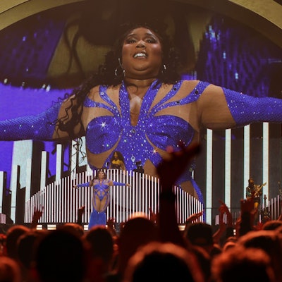 Lizzo steht in einem blau glitzernden Einteiler auf der Bühne der Lanxess-Arena.