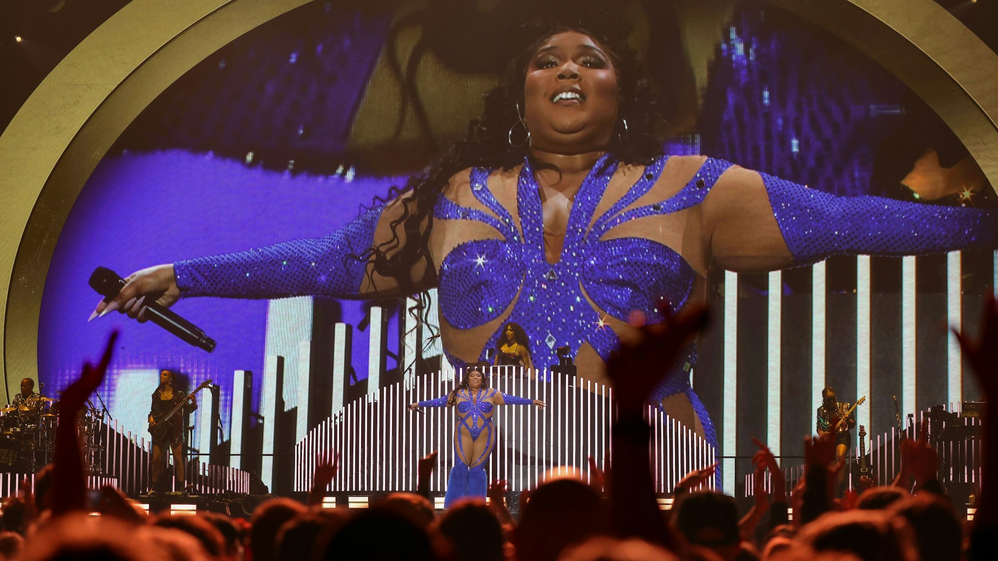 Lizzo steht in einem blau glitzernden Einteiler auf der Bühne der Lanxess-Arena.