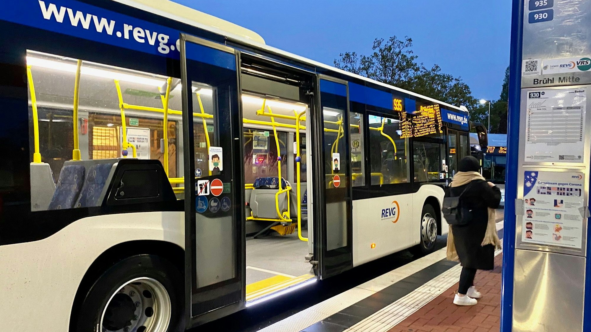 Ein Bus steht mit offenen Türen an einer Haltestelle.