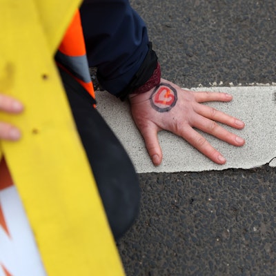 Eine Hand ist auf dem Asphalt festgeklebt.