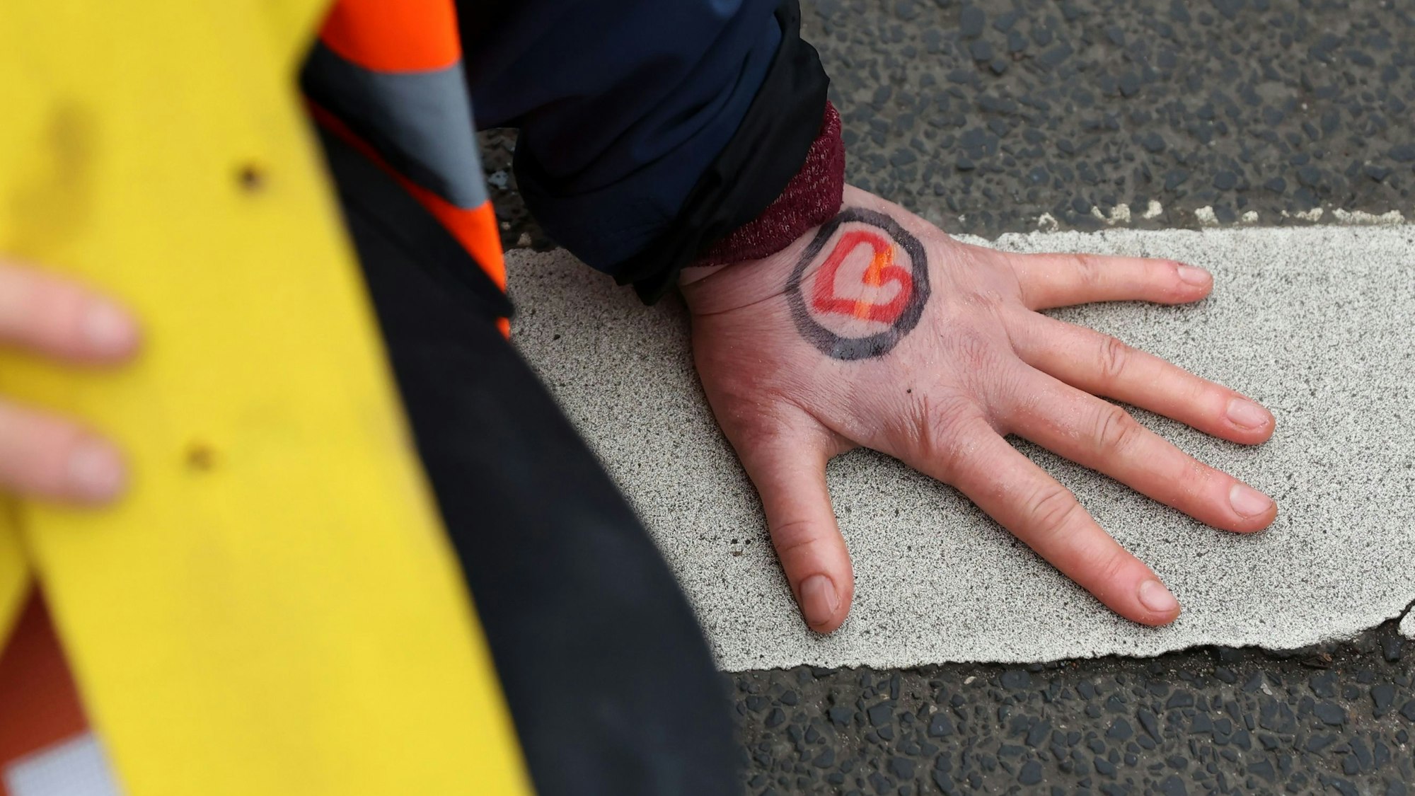 Eine Hand ist auf dem Asphalt festgeklebt.