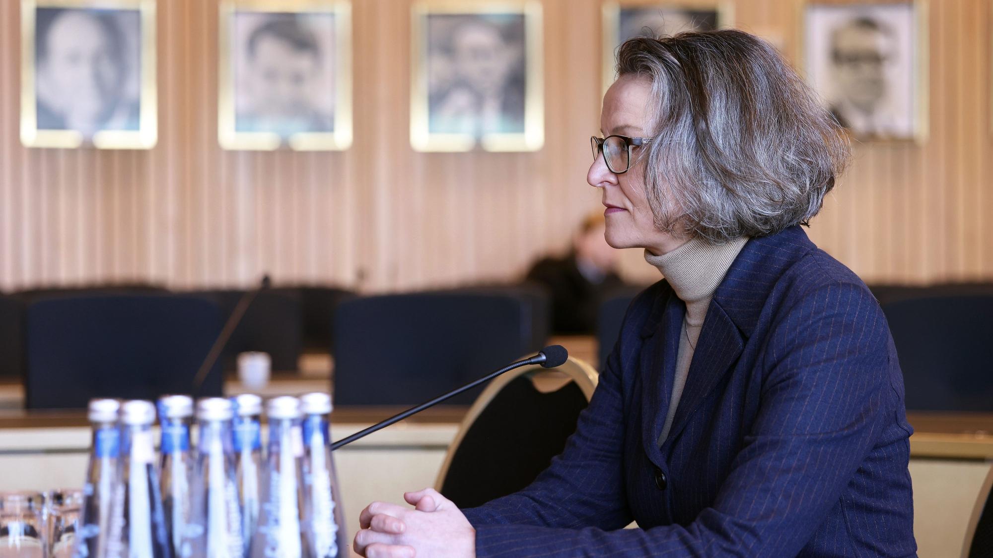 Ministerin Ina Scharrenbach (CDU) ist im Halbprofil zu sehen; sie sitzt am Mikrofon, trägt einen dunkelblauen Blazer und einen beigen Rollkragenpullover. Sie schaut ihr Gegenüber konzentriert an.
