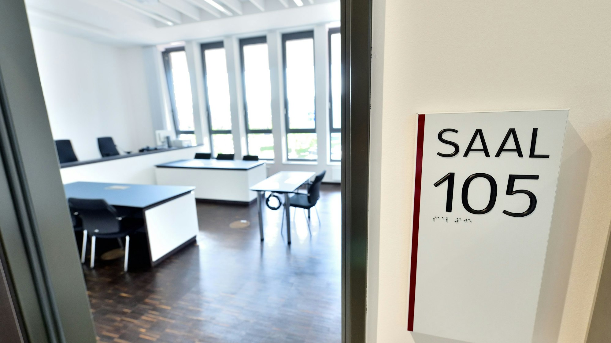 Blick in einen Gerichtssaal mit Tischen und Stühlen.