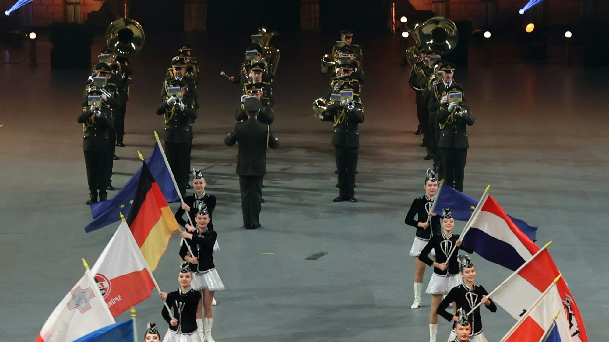 Fahnenträger der beteiligten Nationen vorne im Bild, dahinter ein Militärorchester