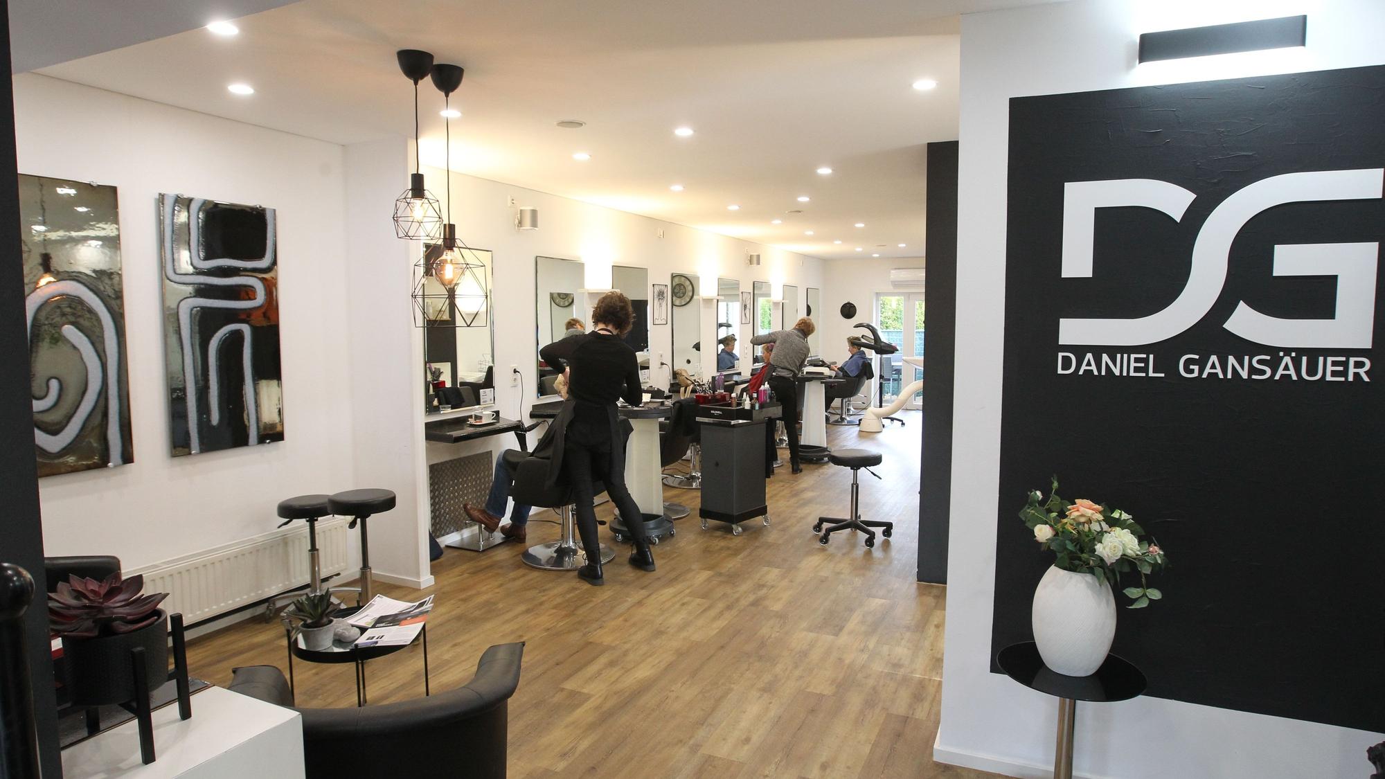 Die Räumlichkeiten des Friseursalons. Im Hintergrund sind Mitarbeiter, die Kunden betreuen.