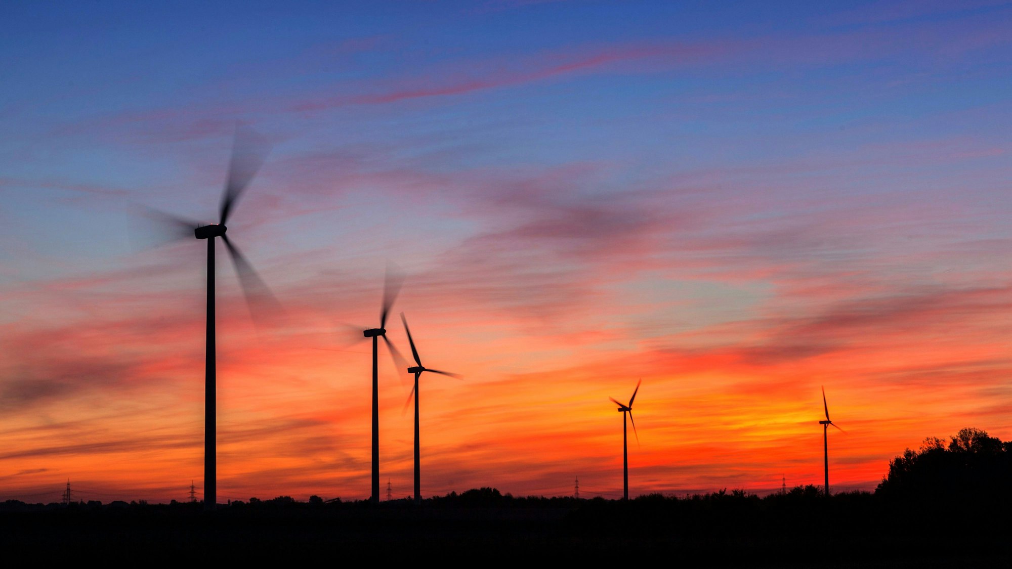 Windkrafträder am Morgen in der Nähe von Düsseldorf. Hinter ihnen geht die Sonne auf.