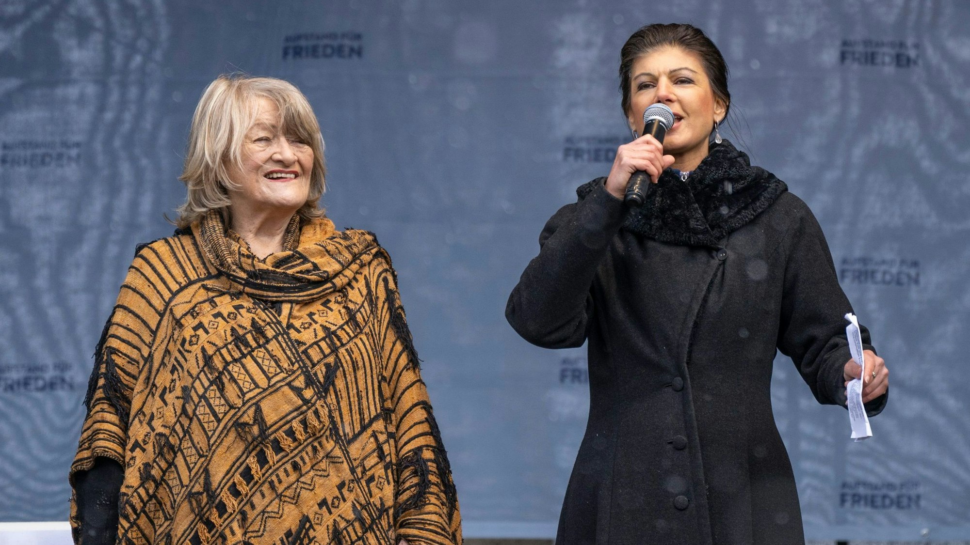 Alice Schwarzer (l.) und Sahra Wagenknecht (r.), stehen beim „Aufstand für den Frieden“ auf der Bühne. Die Publizistin und die Linken-Politikerin hatten zuvor erklärt, es sei Zeit, ihnen zuzuhören. Wenn man das tut, fragt man sich allerdings schnell, warum man das tun sollte.