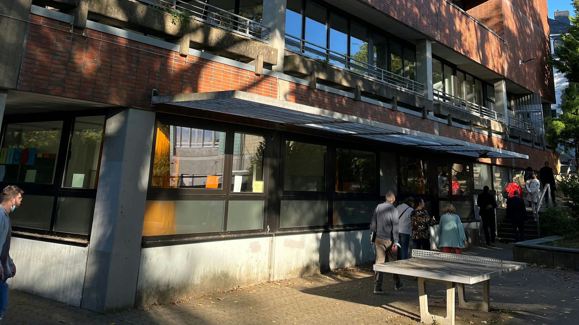 Schüler gehen an einem Schulgebäude entlang.