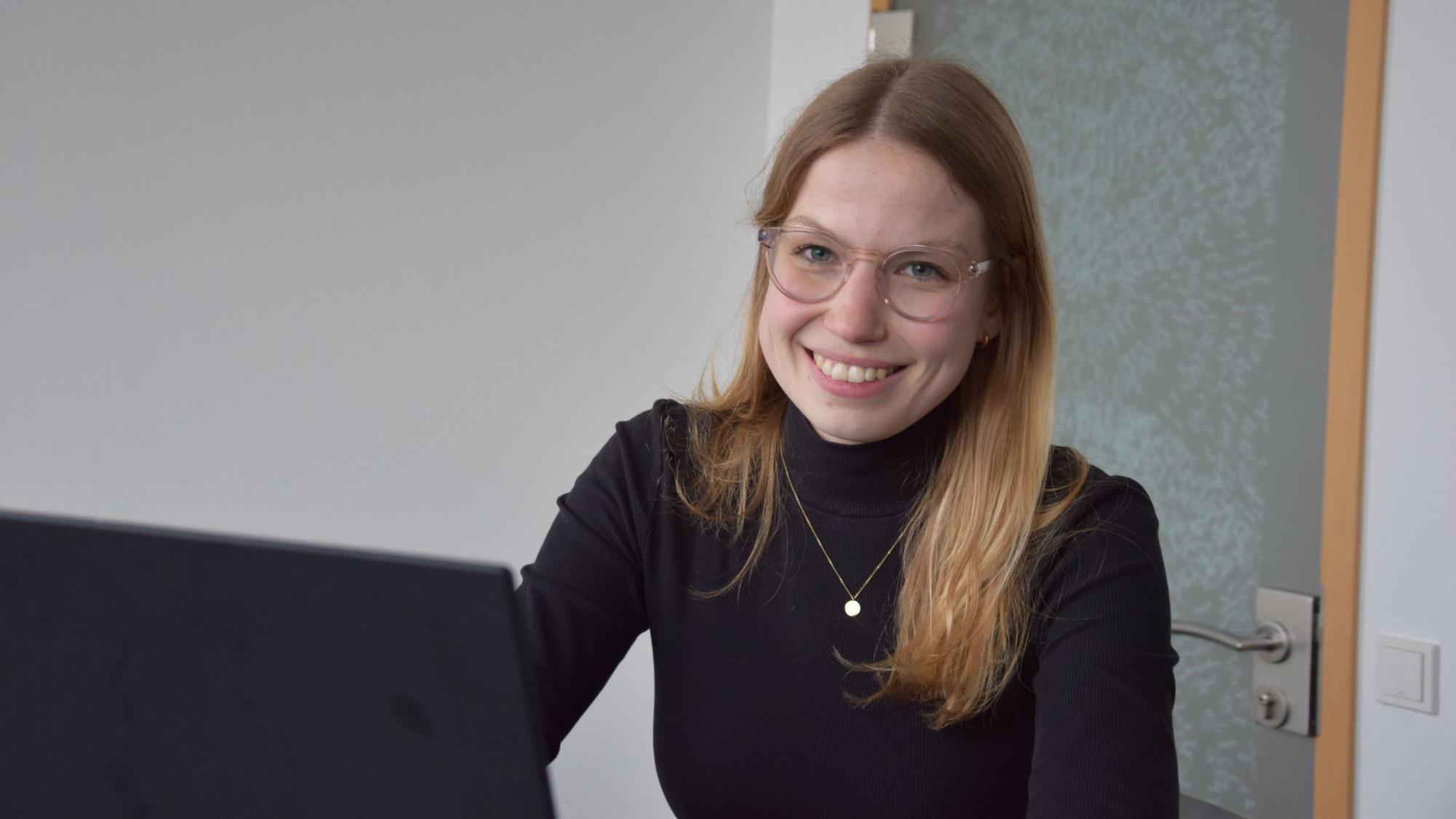 Mareen Diesen sitzt vor ihrem Laptop und lächelt in die Kamera.