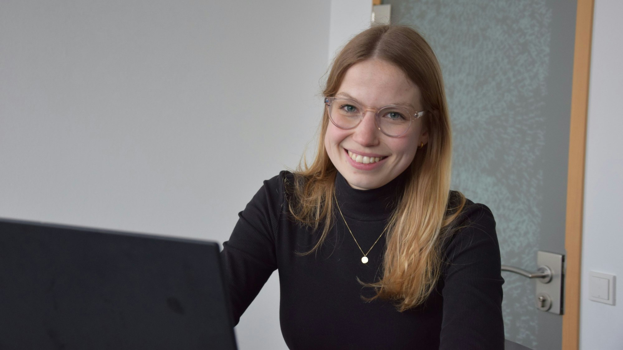 Mareen Diesen sitzt vor ihrem Laptop und lächelt in die Kamera.