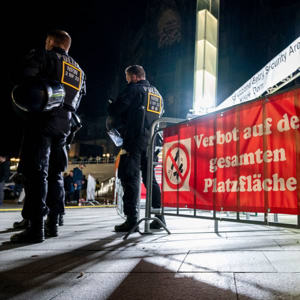 Polizisten stehen in der Nacht vor einem Feuerwerks-Verbotsschild.
