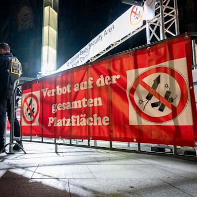 Polizisten stehen in der Nacht vor einem Feuerwerks-Verbotsschild.