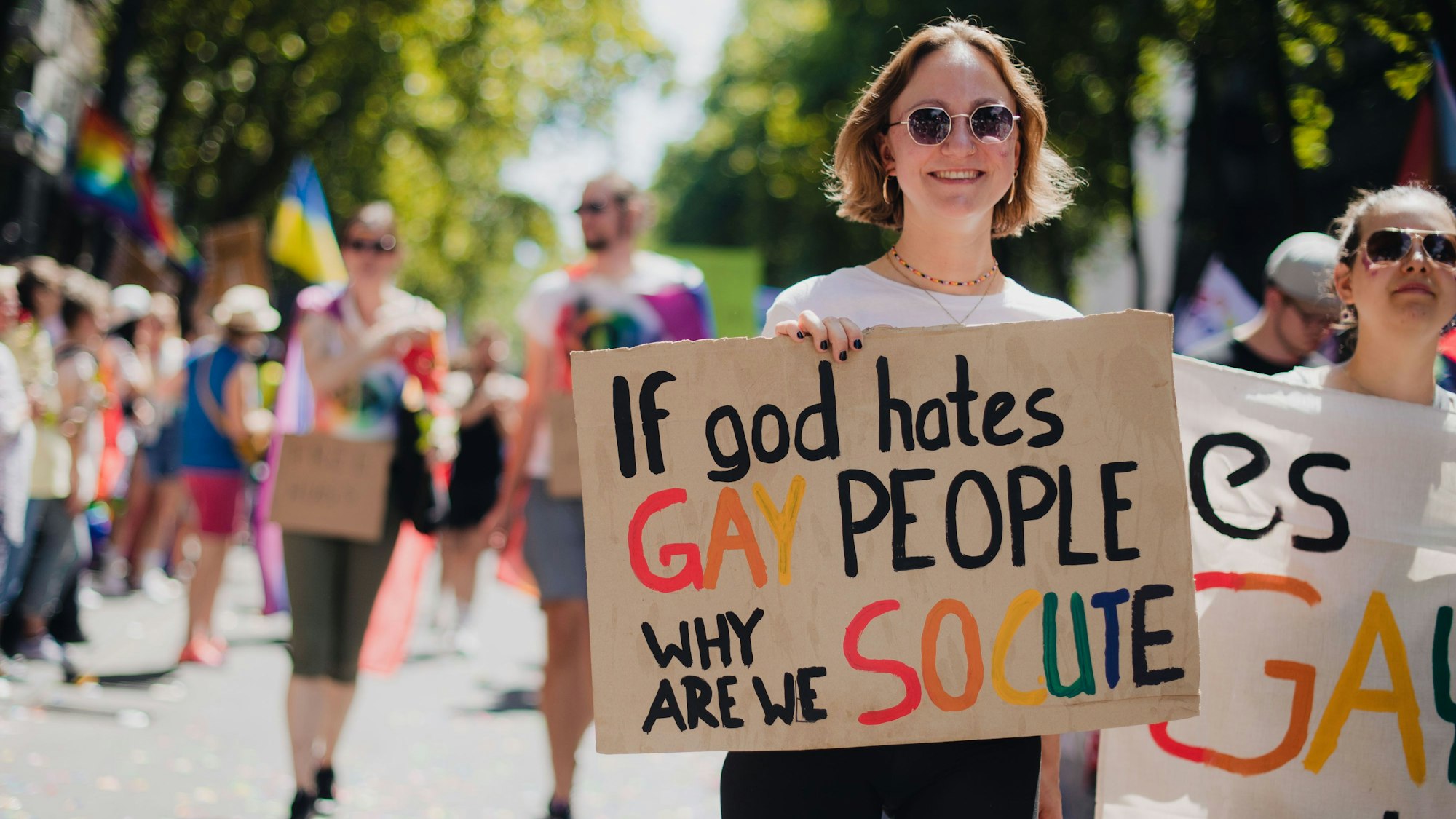 Eine Frau nimmt an der CSD-Demo zum Christopher Street Day (CSD) in Köln teil - sie trägt ein Schild mit der Aufschrift „If god hates gay people, why are we so cute“. Hunderttausende Zuschauer werden zu der Demonstration erwartet. Der Kölner CSD ist eine der größten Veranstaltungen der LGBTIQ-Community in Europa.
