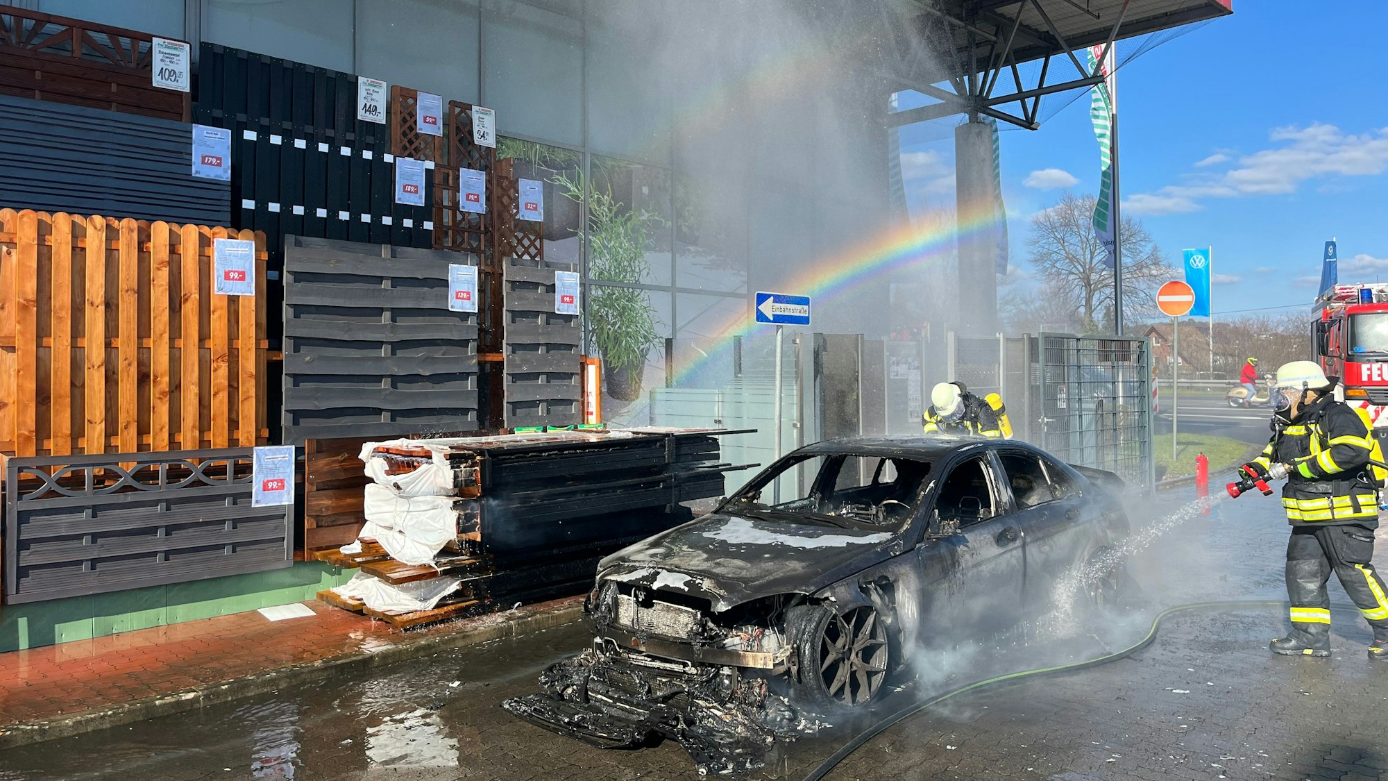 Ein Feuerwehrmann löscht ein brennendes Auto.