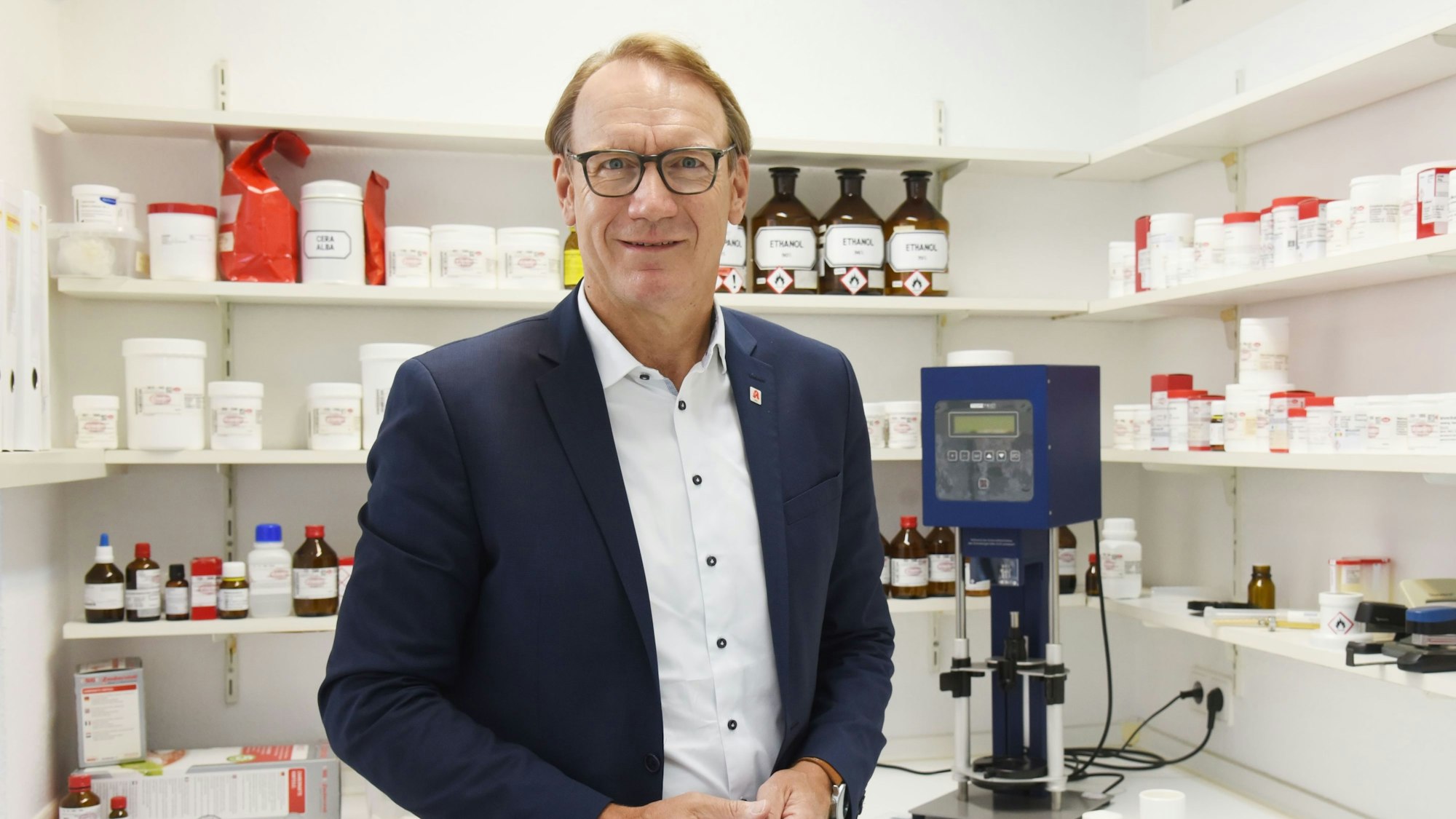 Thomas Preis, Chef des Apotheker Verbandes Köln und Nordrhein, in einer Apotheke vor Fläschchen und Dosen.