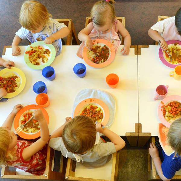 Kinder sitzen am in einer Kindertageseinrichtung beim Mittagessen.
