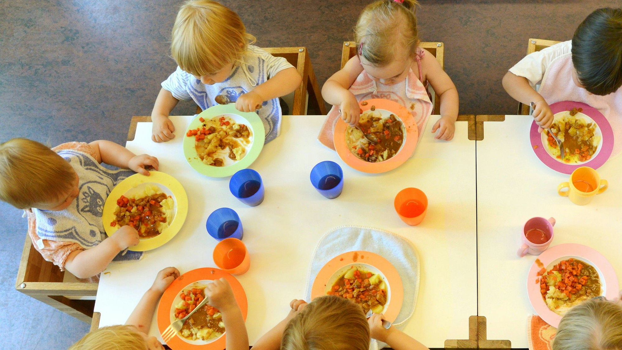 Kinder sitzen am in einer Kindertageseinrichtung beim Mittagessen.