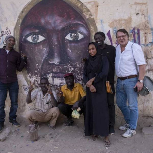 Hans Mörtter (r.) und Hassan Magdi (l.) mit anderen in Khartum vor einem Wandbild, das die 2012 erschossene Parlamentarierin Awasia Ajbna zeigt.
