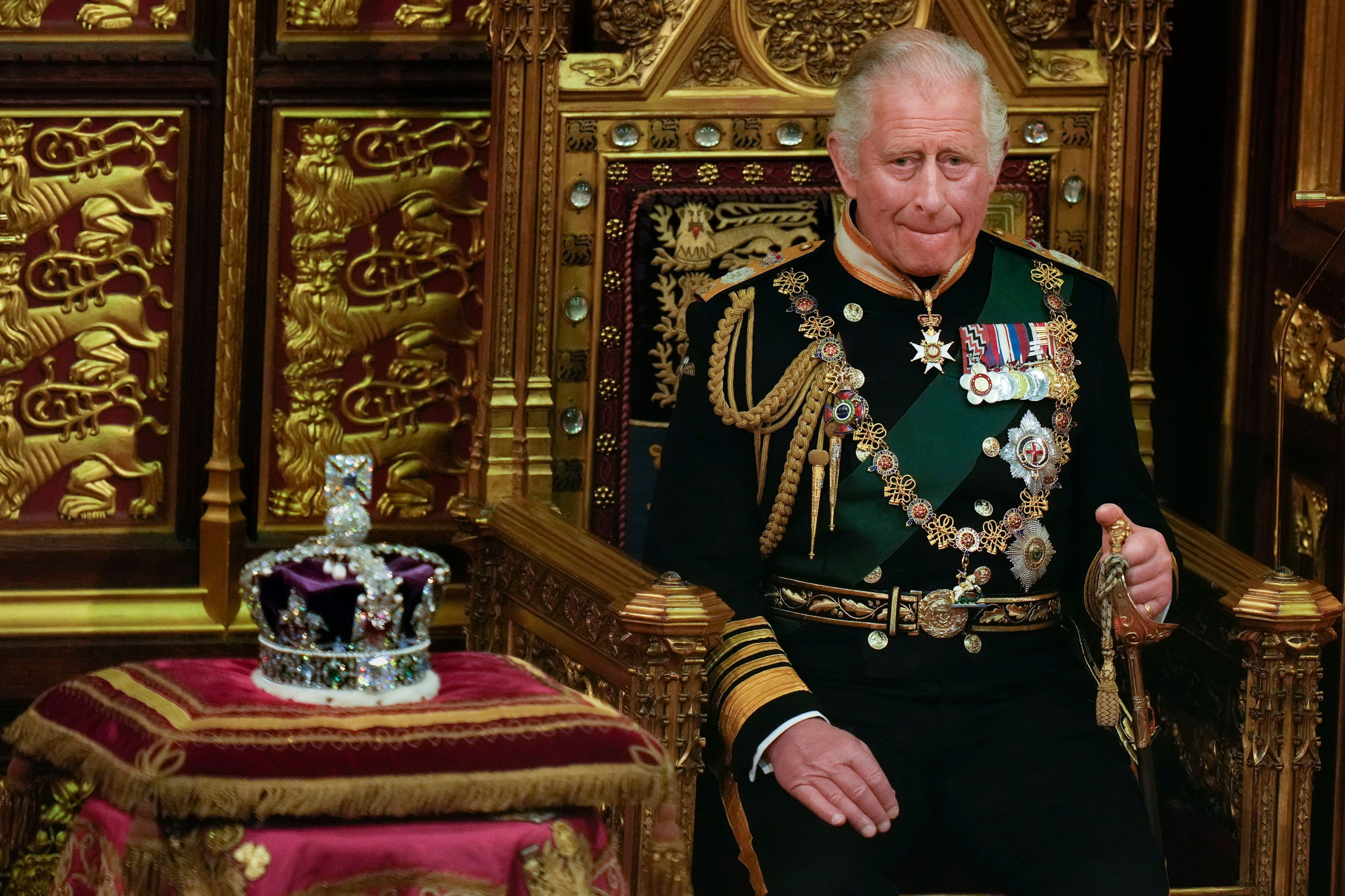 König Charles III. auf dem Thron. Neben ihm die Krone.