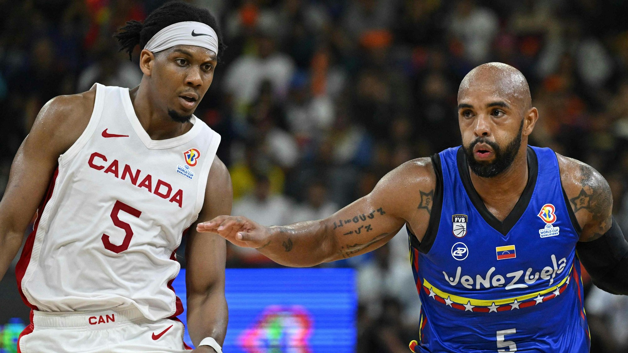 Canada's Kadre Gray (L) marks Venezuela's Gregory Vargas during their FIBA Basketball World Cup 2023 Americas qualifiers match at the Poliedro in Caracas , on February 26, 2023. - fouls (Photo by Federico PARRA / AFP)