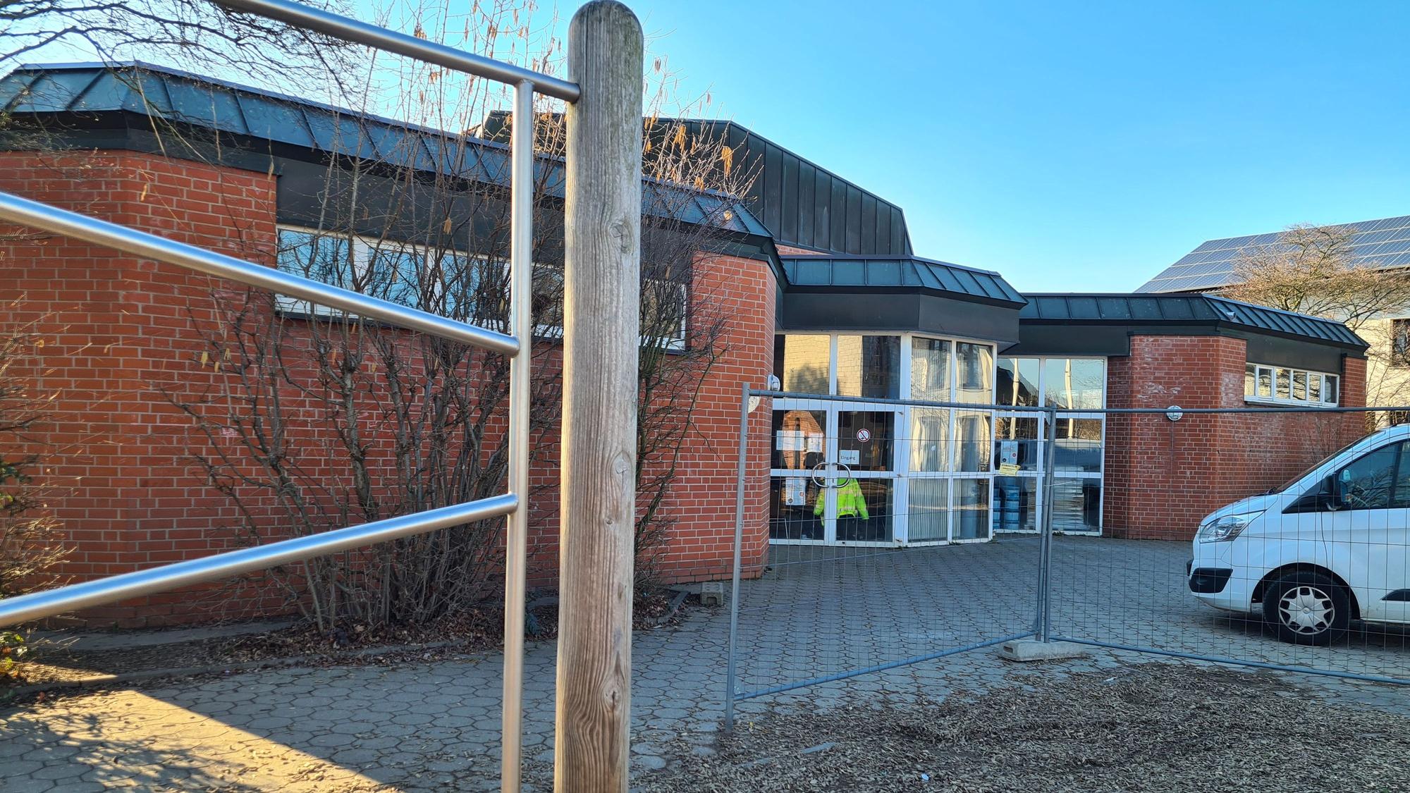 Blick auf die Halle an der Ulrichschule in Sindorf, vorne steht ein Bauzaun.