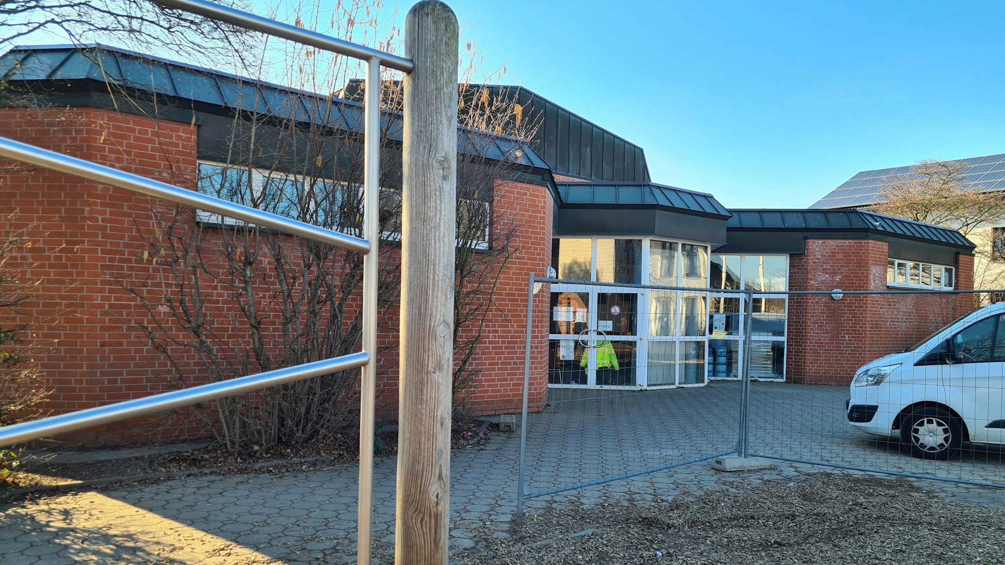Blick auf die Halle an der Ulrichschule in Sindorf, vorne steht ein Bauzaun.