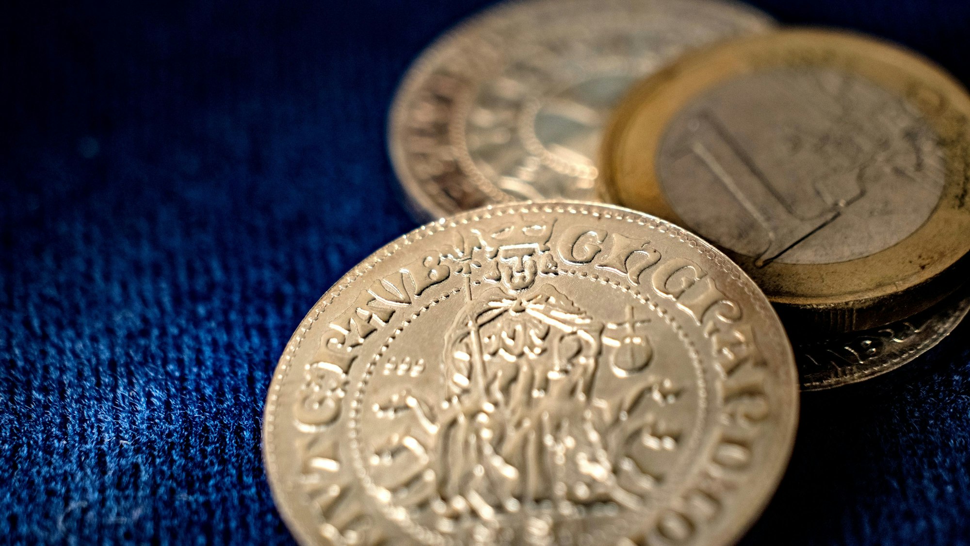 Die Nachprägung eines Wipperfürther Doppelschillings liegt mit einer 1-Euro-Münze auf dunklem Untergrund.