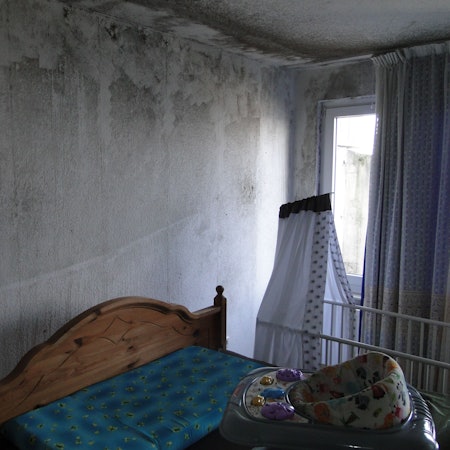 Ein Schlafzimmer, dessen Wände großflächig von schwarzem Schimmel befallen sind