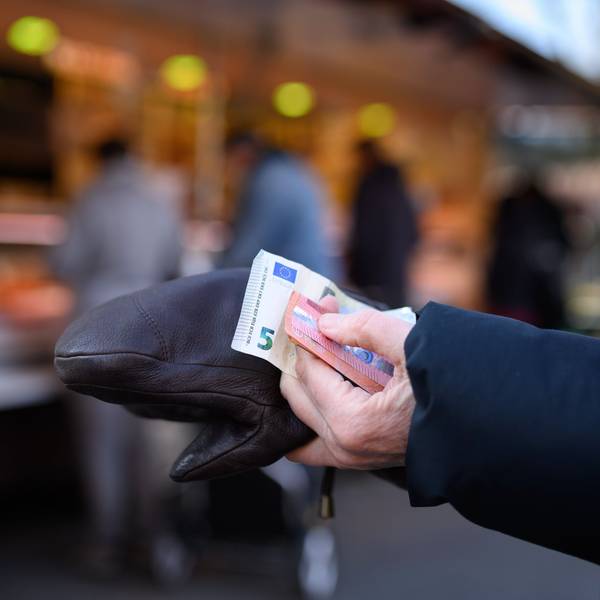 Eine Frau steht an einem Stand an und hält das Bargeld für ihren Einkauf in der Hand bereit.