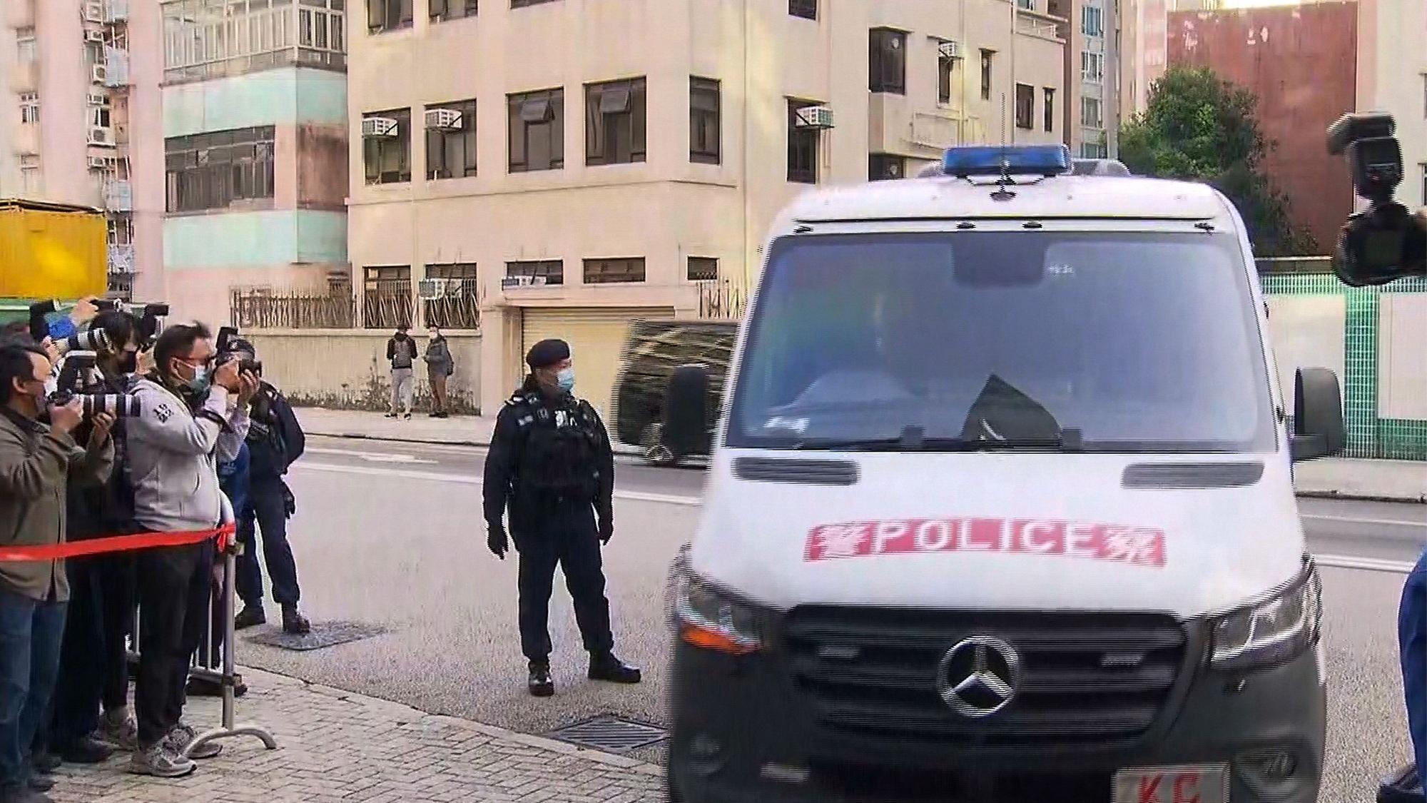 Polizei von Hongkong in einem Wagen, daneben Paparazzis.